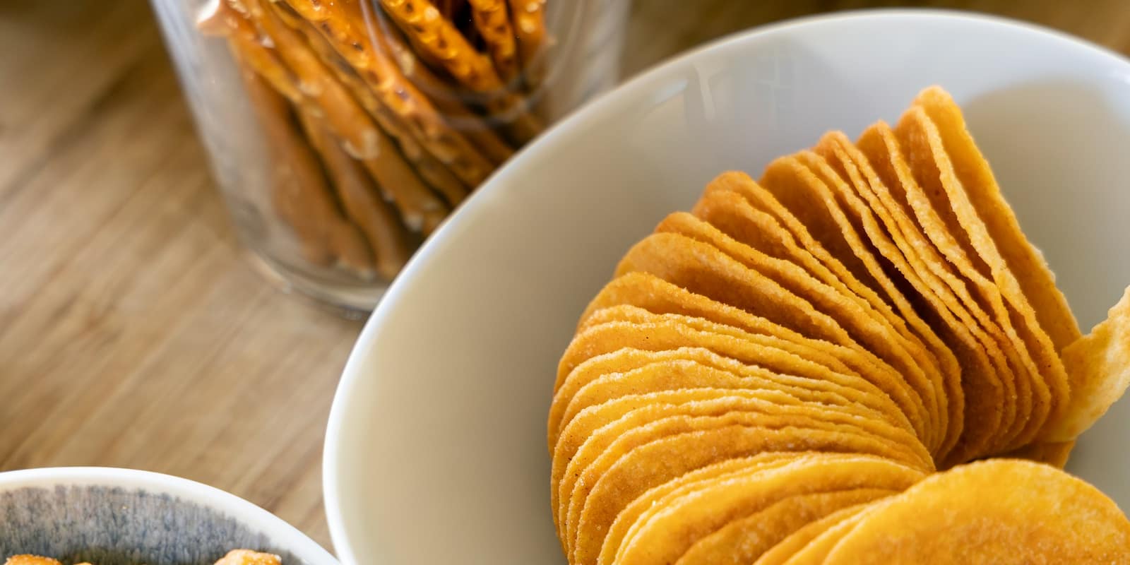 Bowls of chips and snacks crowded onto a wooden table.